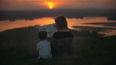 Anne oğluyla hill sivrisinekler yaz gün batımında harekâta bir kitap okuma