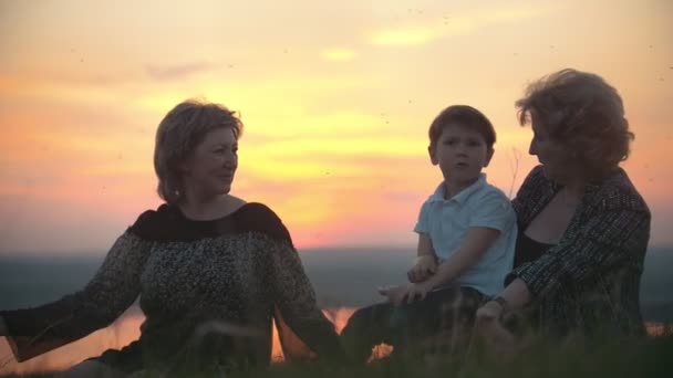 Grootmoeder, moeder met zoontje op de heuvel swatting bij muggen bij zonsondergang — Stockvideo