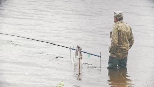 Старик рыбачит на реке — стоковое видео