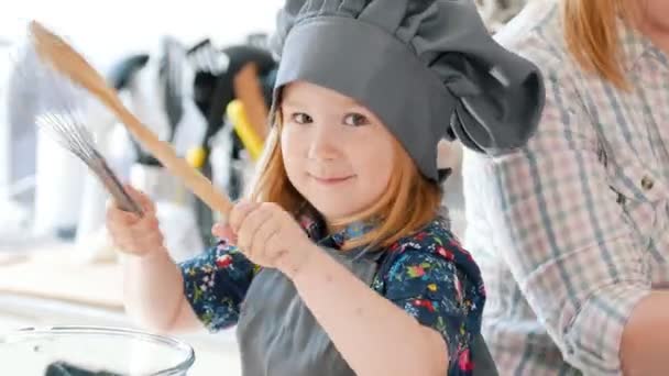 Niña jugando con cuchara y batidor en la cocina — Vídeo de stock