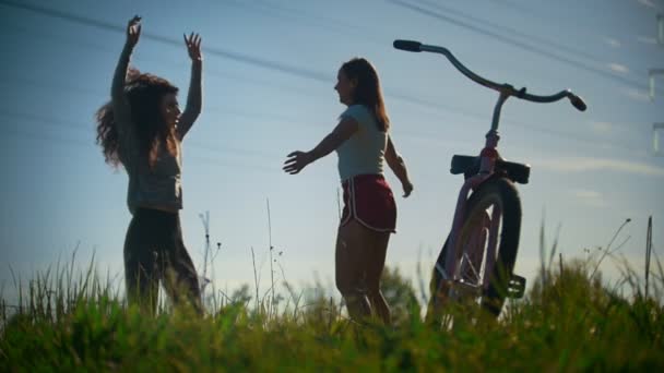 Dos chicas jóvenes se calientan, saltar antes de un paseo en bicicleta, día soleado — Vídeo de stock