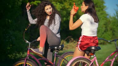 Dinlenme bir bisiklete binmek, iki kadın bisikletçiler içecek su ve konuşmak, güneşli yaz gün