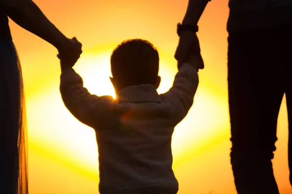 Ребенок держит за руки родителей на солнце — стоковое фото