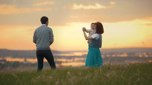 Jovem casal com uma criança dançando e se divertindo na natureza, pôr do sol — Vídeo de Stock
