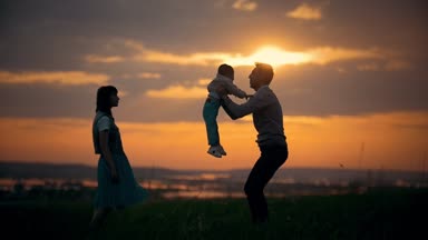 Babası oğlunu havada, bir yaz akşamında atar, Aile güneşin arka plan üzerinde duruyor