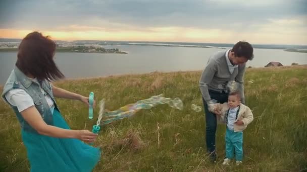 Paar plezier met baby op het veld, bubbels baby zeep lachen — Stockvideo