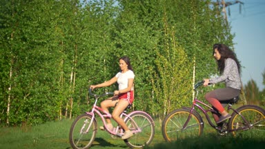 Bisiklet Park güneşli bir günde yeşil ağaçların arka plan üzerinde güzel kızlar