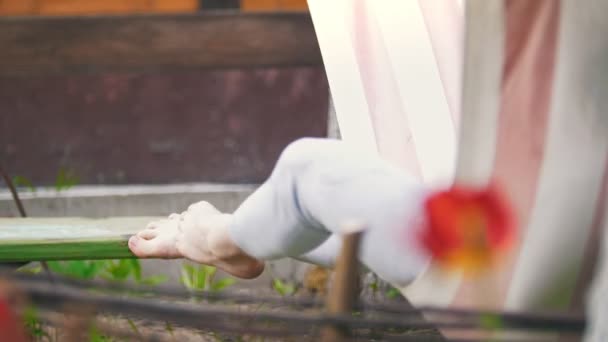 女孩摇摆在吊床在庭院 腿垂悬 夏天天 远摄射击 — 图库视频影像