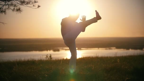 Il combattente fa calci di gambe in un giro sullo sfondo del sole al tramonto, rallentatore — Video Stock