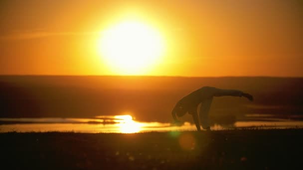 Bir adam gerçekleştirir akrobatik stunts, takla, turuncu günbatımı, ağır çekim — Stok video