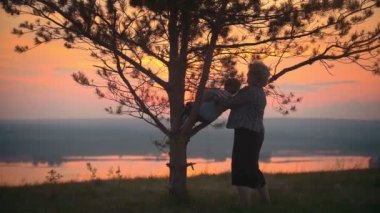 Büyükanne ve torunu yaz günbatımı kullan ve Büyükanne torunu bir ağaca tırmanmak yardımcı olur