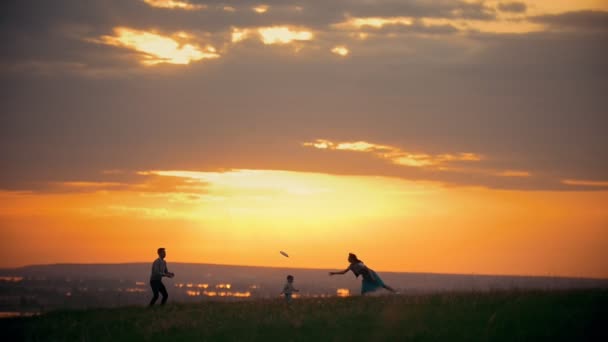 Les parents jouent une assiette d'air, un enfant essaie de l'attraper, coucher de soleil — Video