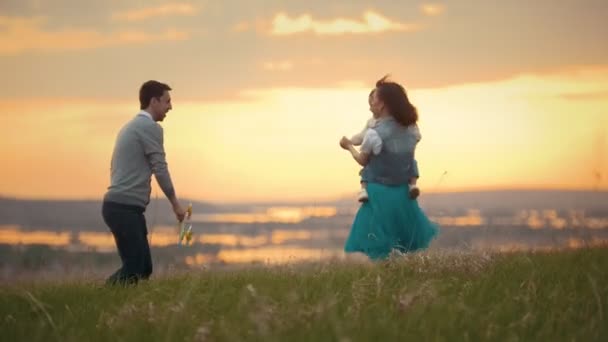 Jeune couple avec un enfant dansant et s'amusant dans la nature, coucher de soleil — Video