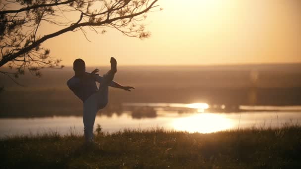Luchador hace patada pierna, puesta de sol en el río — Vídeo de stock