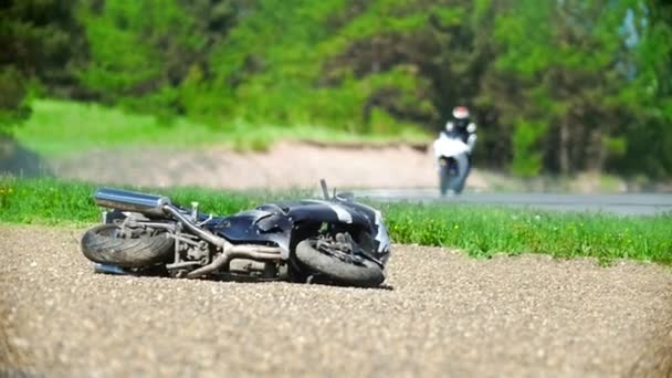Motorcykeln ligger på vägarna, i bakgrunden föraren åkattraktioner, slow motion — Stockvideo