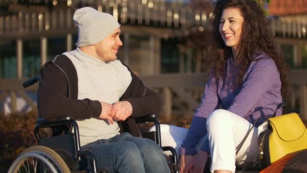 愉快的夫妇-残疾的年轻人在轮椅与年轻妇女一起享受日落 — 图库视频影像