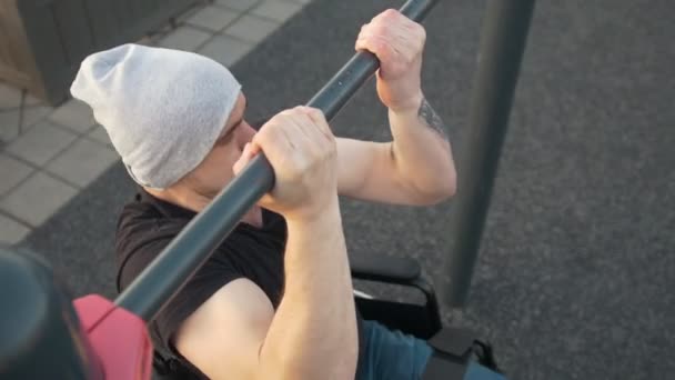 Muskularny mężczyzna niepełnosprawnych na wózku inwalidzkim ciągnie się na poprzeczkę na zewnątrz — Wideo stockowe