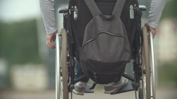 Homem com deficiência em uma cadeira de rodas andando na rua da cidade — Vídeo de Stock