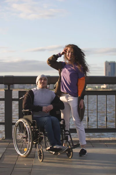 Щаслива пара - молода жінка з інвалідом у інвалідному візку відпочиває разом на відкритому повітрі — стокове фото