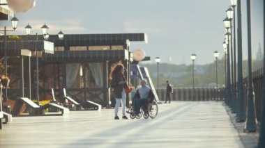 Tekerlekli sandalyeli Engelli adam genç kadının fotoğrafını o quay adlı alır.