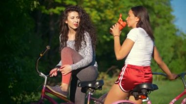 İki genç bisikletçiler iletişim ve parkta Bisiklete binme gezisinde bir güneşli yaz günü gülmek