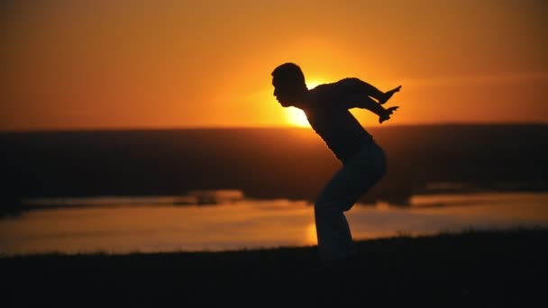 Acrobat makes wheel back, setting sun, slow-motion — Stock Video