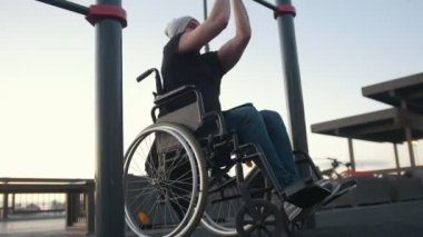 Genç adam açık havada kol demiri üzerinde meşgul tekerlekli sandalyede devre dışı
