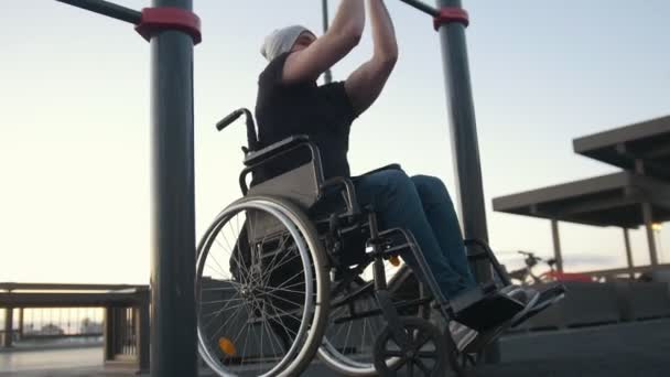 Молодий інвалідний чоловік у інвалідному кріслі, зайнятий на перехресті на відкритому повітрі — стокове відео