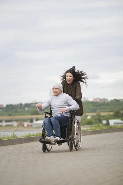Beautiful woman with happy disabled man having fun outdoors in cloudy day