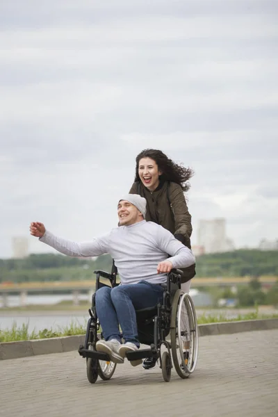 Fröhliche Frau mit jungem behinderten Mann im Rollstuhl am Kai — Stockfoto