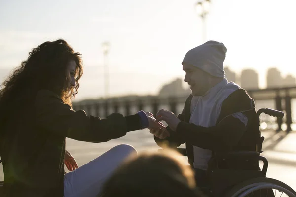 Junger behinderter Mann im Rollstuhl macht seiner Freundin im Sonnenlicht einen Heiratsantrag — Stockfoto