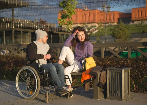 Junge Frau mit behindertem Mann im Rollstuhl am Kai genießt Sonnenlicht — Stockfoto