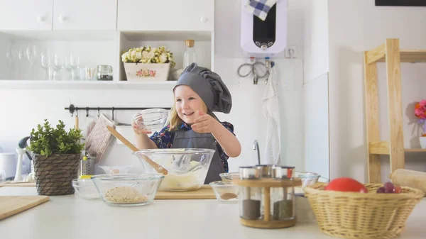 Счастливая маленькая девочка пекарь собирается испечь печенье на кухне — стоковое фото