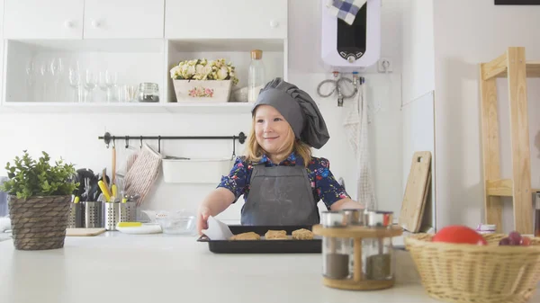 Пекарь дошкольного возраста держит простыню с печеньем — стоковое фото