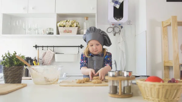 Пекарь-дошкольница кладет печенье на простыню — стоковое фото
