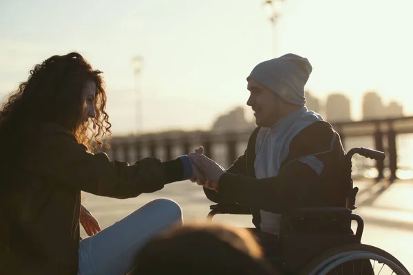 Junger behinderter Mann im Rollstuhl macht seiner Freundin im Sonnenlicht einen Heiratsantrag — Stockfoto