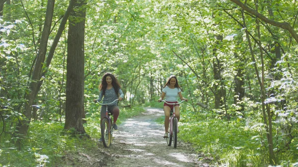 Dvě dívky chodit s jízdní kola v zeleném lese, letní den — Stock fotografie