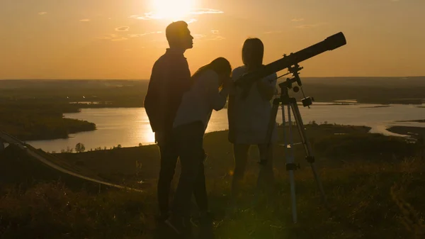 Junge glückliche Freunde blicken durch das Fernrohr und amüsieren sich bei sommerlichem Sonnenuntergang — Stockfoto