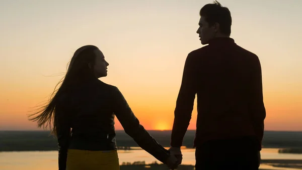 爱的年轻夫妇牵手看着对方在惊人的日落户外 — 图库照片