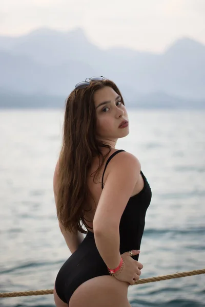 Potret wanita muda yang cantik berdiri oleh laut di latar belakang pegunungan — Stok Foto