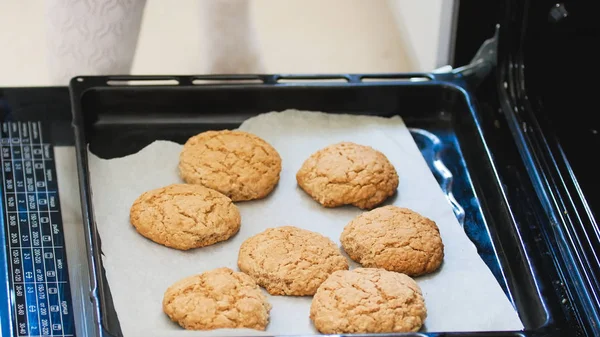 Рука в варежке вытаскивает из духовки домашнее печенье — стоковое фото
