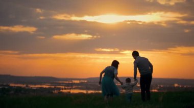 Açık yürüyüş mutlu geleneksel aile - anne, baba ve küçük oğlu - yaz çayır günbatımında için