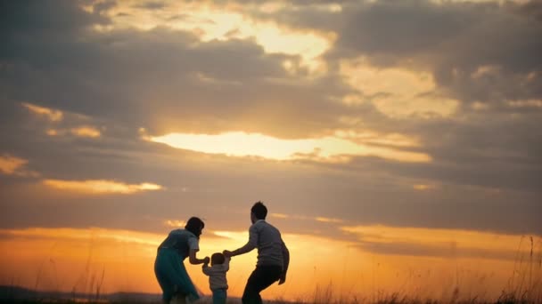 Padre lanza a su pequeño hijo en el aire, una noche de verano, puesta de sol — Vídeo de stock