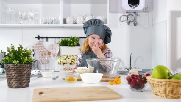 Okul öncesi kız baker mutfak üzerinde karışımları ve bir kase hamur tadı — Stok video