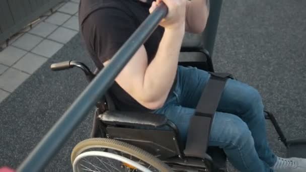 Мускулистый инвалид в инвалидной коляске останавливается на перекладине на открытом воздухе — стоковое видео