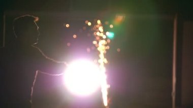 Genç adam gerçekleştirme kıvılcımlar arasında geceleri ellerinde çevirir