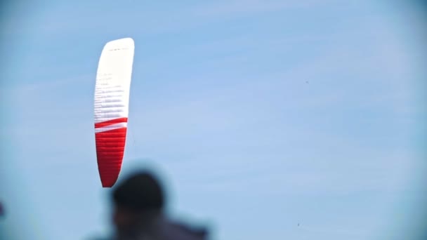 Fliegendes Segel bei blauem Himmel mit Kiteboarder über den Fluss — Stockvideo