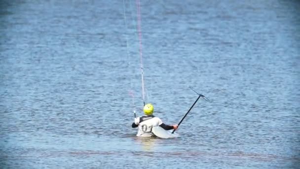 Muž stojí ve vodě a nastaví plachtu pro kitesurfing — Stock video