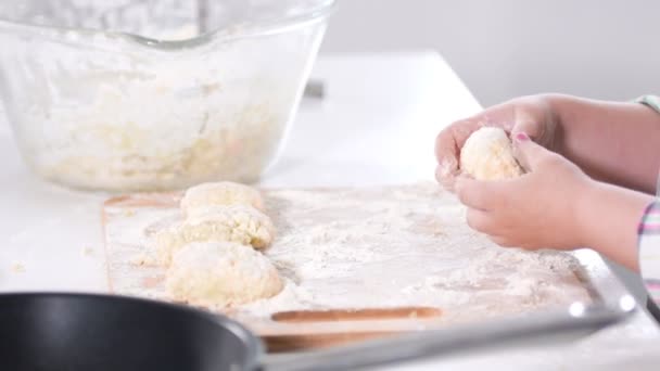 Kis lányok kezében sculpts Túrós palacsinta tészta a konyhában — Stock videók