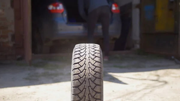 Car wheels rolling on the ground in front of car garage